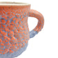 Detail picture of fired mug with orange supergloop glaze over blue puff glaze.
