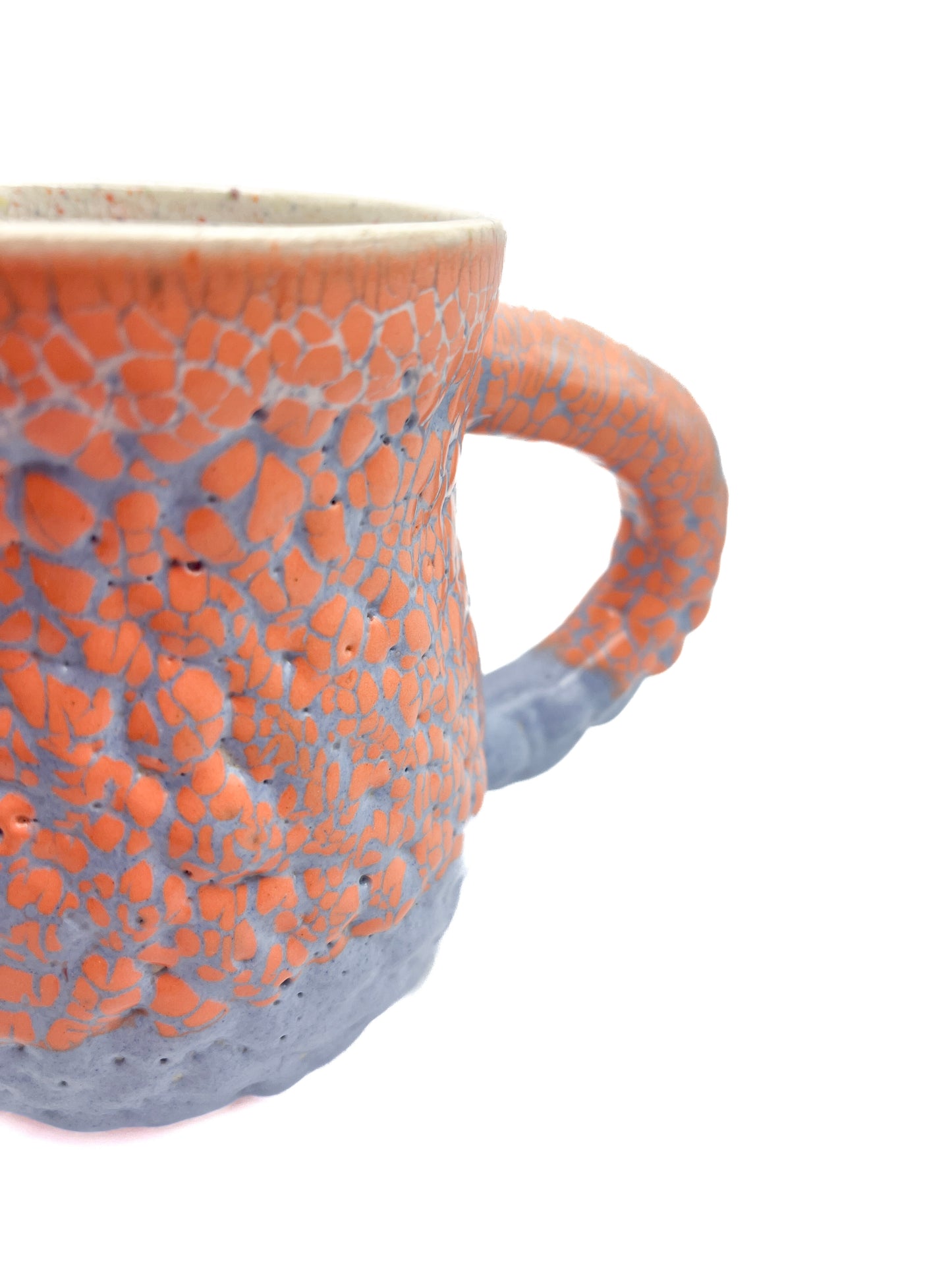 Detail picture of fired mug with orange supergloop glaze over blue puff glaze.