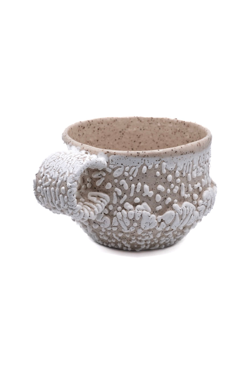 Fired mug for white bead glaze on light, speckled clay. Gloop-like texture when fired to cone 5 or 6.
