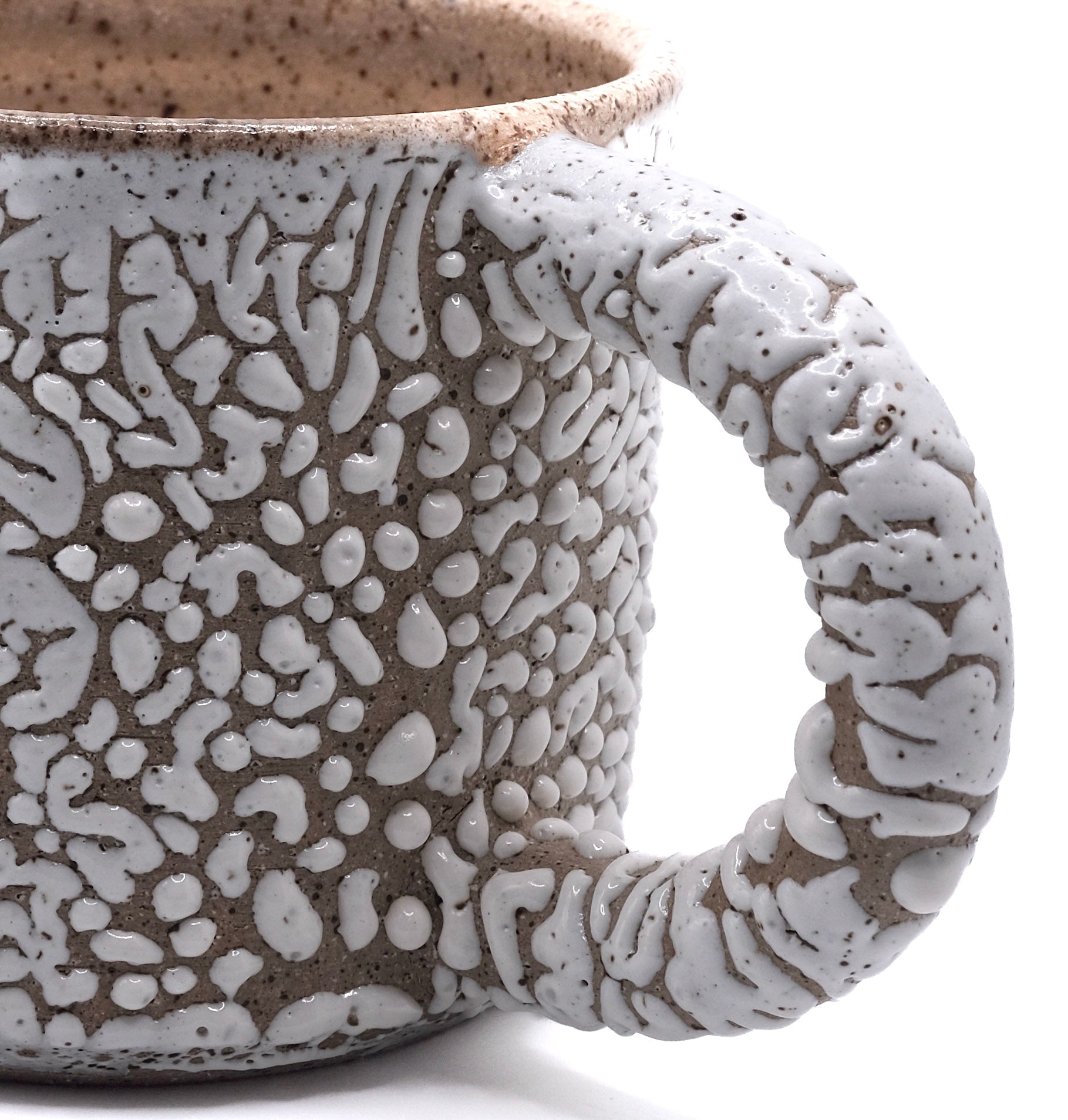 Close-up of fired mug with white bead glaze on dark clay. Gloop-like texture when fired to cone 5 or 6.