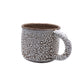 Fired mug with white bead glaze on dark clay. Gloop-like texture when fired to cone 5 or 6.